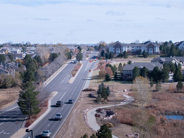 A photo of a low-income neighborhood near a busy highway, with a skyline dominated by industrial smokestacks. The air appears hazy with pollution, and the houses are small and poorly maintained. The image highlights the environmental challenges faced by economically disadvantaged communities.