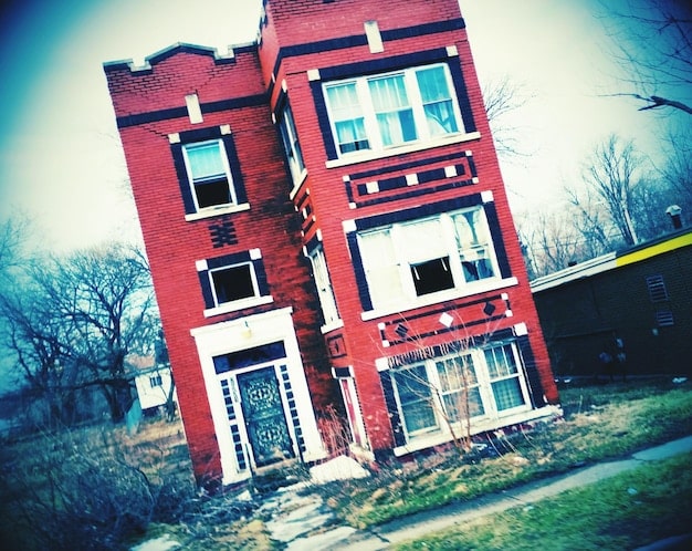 A before-and-after split image showing a run-down building in a low-income neighborhood being renovated into a modern, upscale apartment complex.