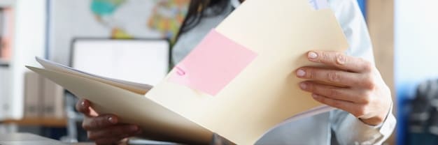 A close-up shot of a person carefully reading a dense document with highlighted sections and sticky notes. The image emphasizes the importance of detailed review and understanding of grant guidelines.