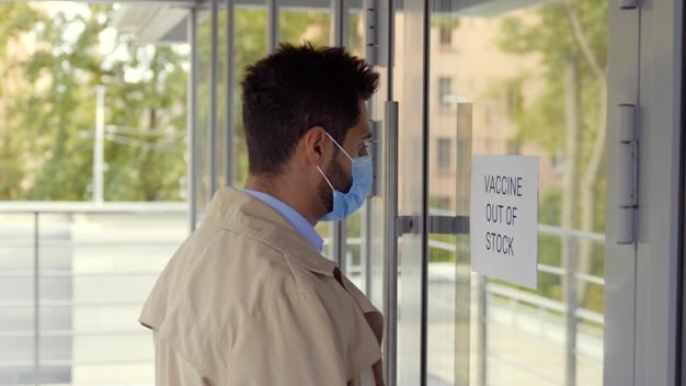 The exterior of a modern community health center, with diverse patients entering and exiting. Signage indicates services such as vaccinations, screenings, and primary care.